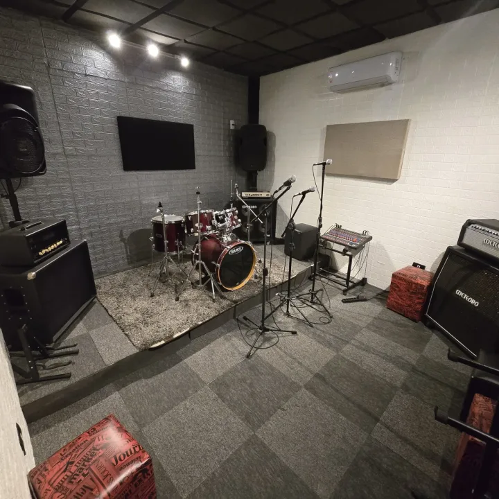 Sala 2 do estúdio com bateria, amplificadores e microfones prontos para a banda
