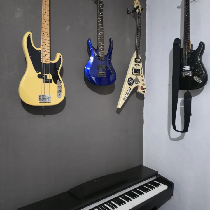 Baixos na parede e piano digital na sala técnica
